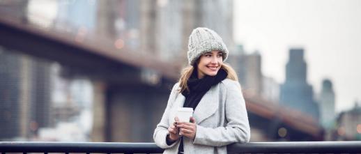 Woman in winter clothing poses on a bridge